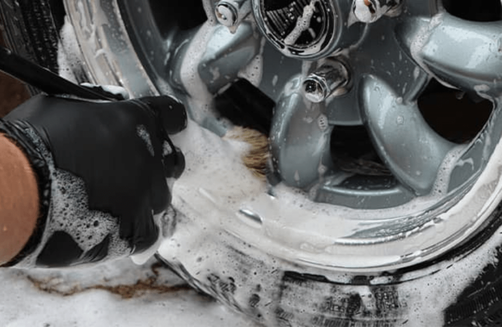 Using detailing brushes to remove dirt and grime from a car's wheels