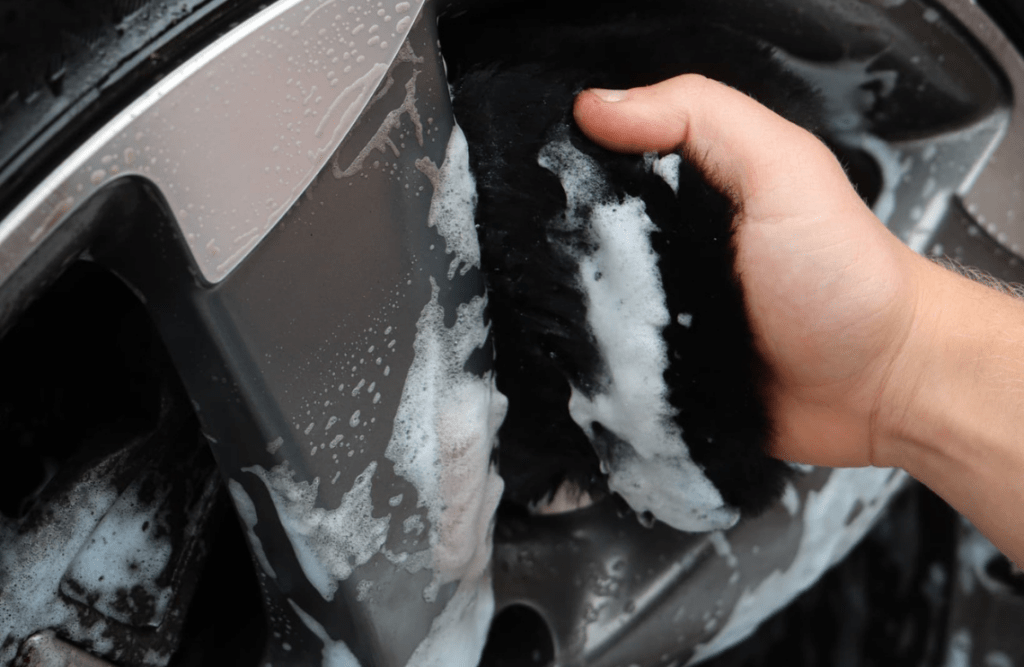Cleaning a car's wheel with a wash mitt 