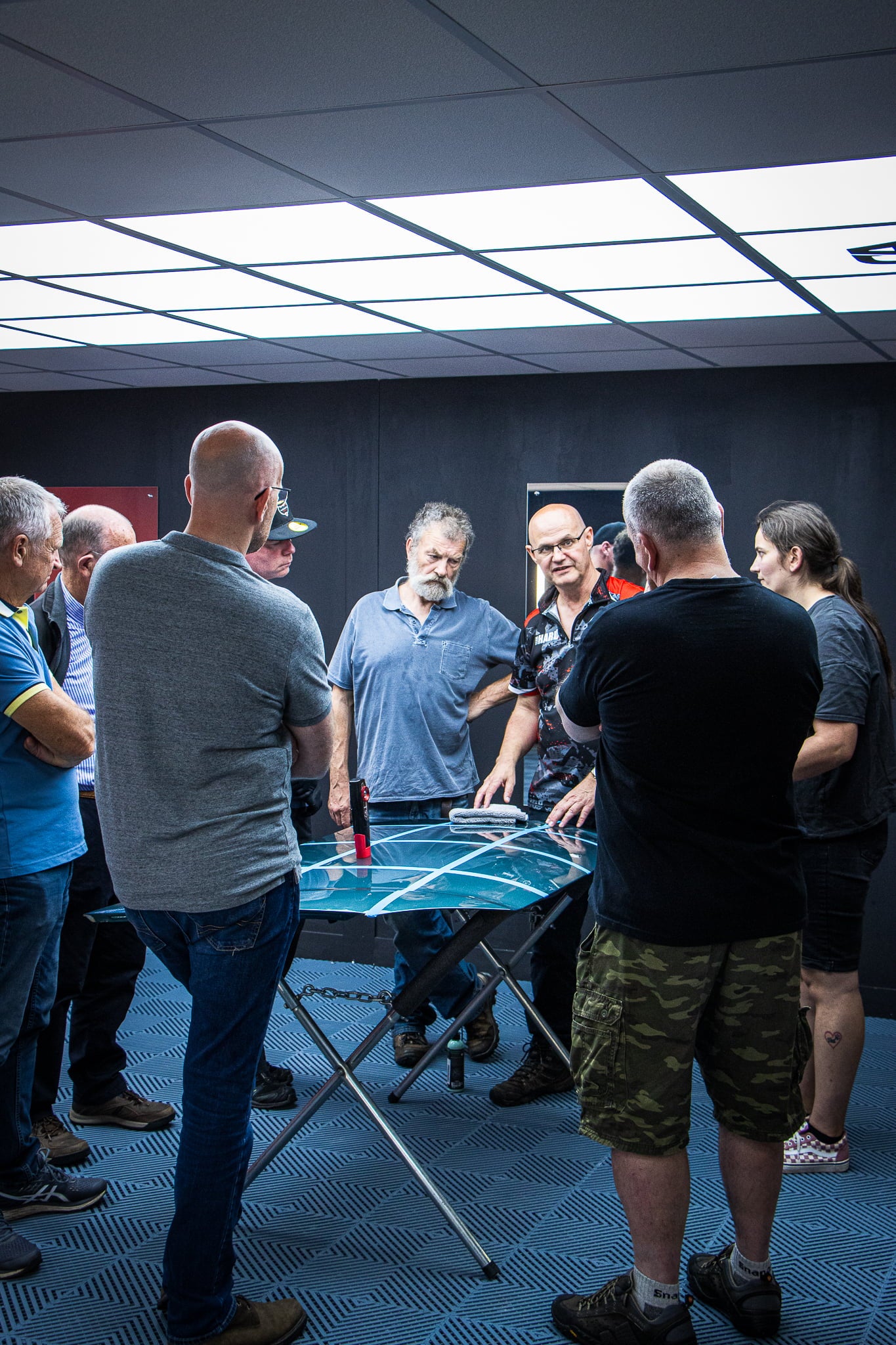 Clive teaching a group if trainees, all standing around a car bonnet