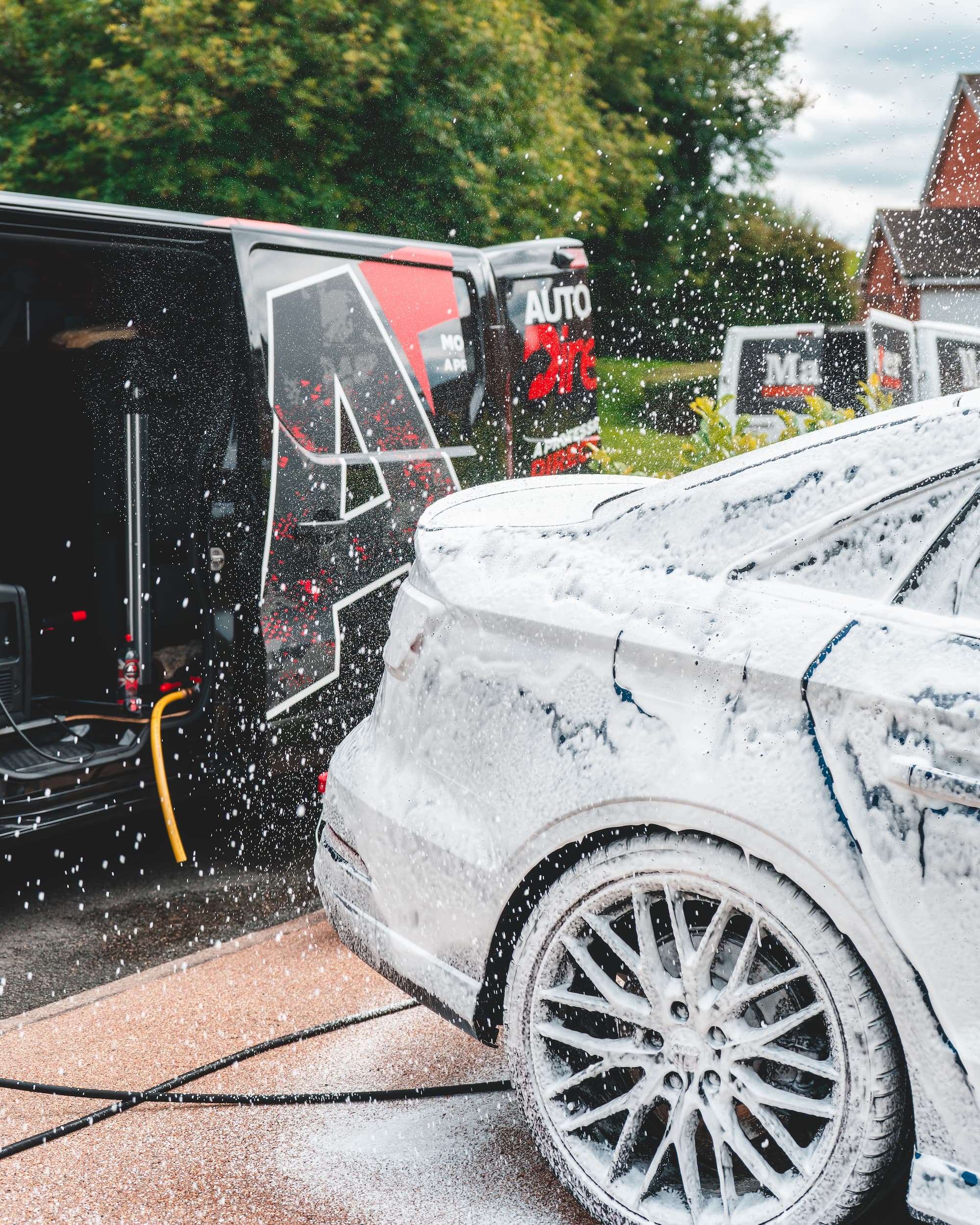 boot of a car being snowfoamed in front of the mobile detailing van