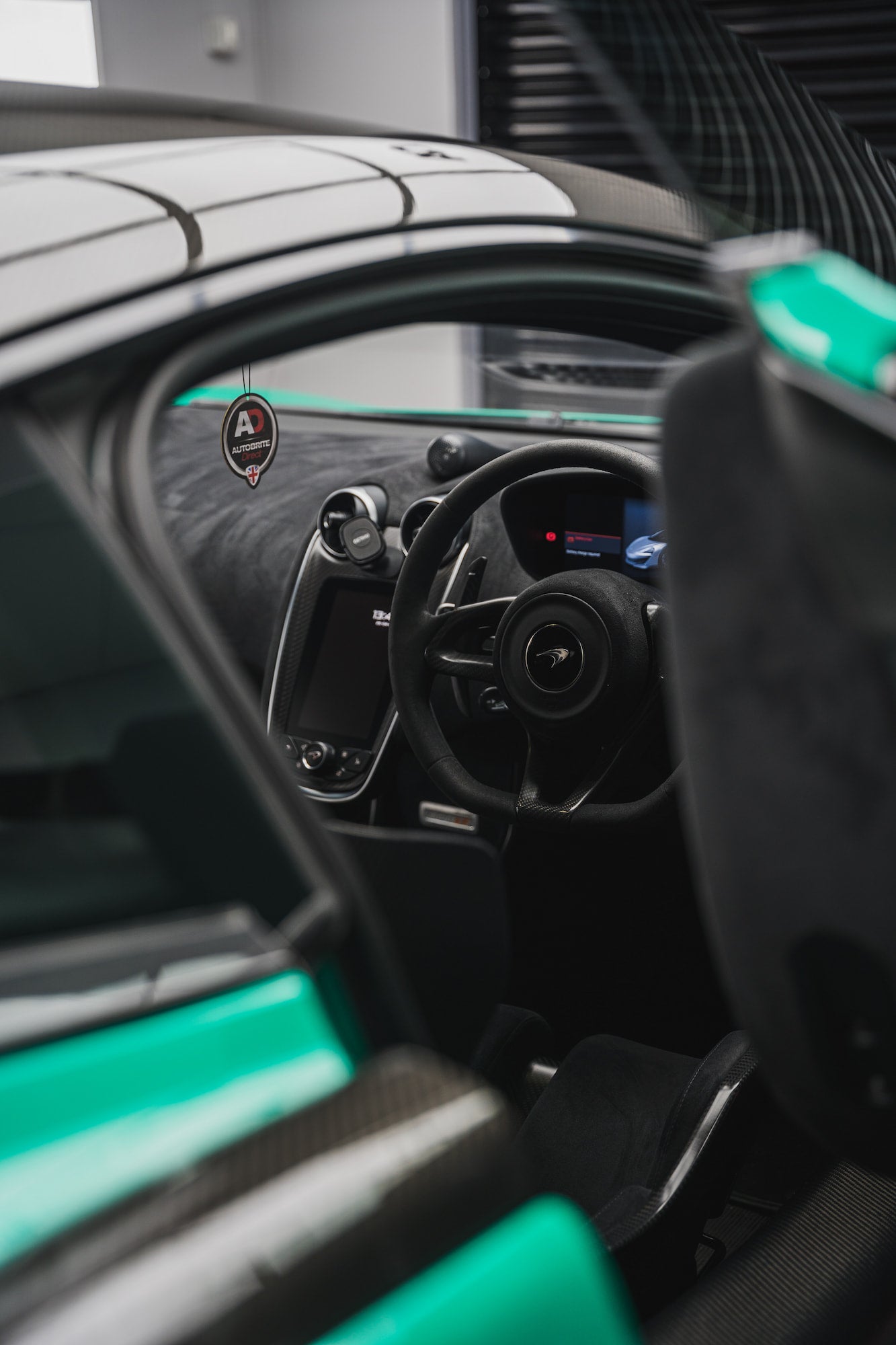 Interior and steering wheel of a green McLaren with an AD hanging air freshener