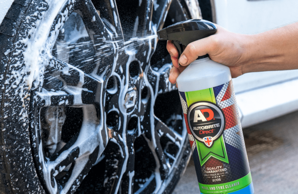 Applying wheel and tyre cleaner to a car's wheels 